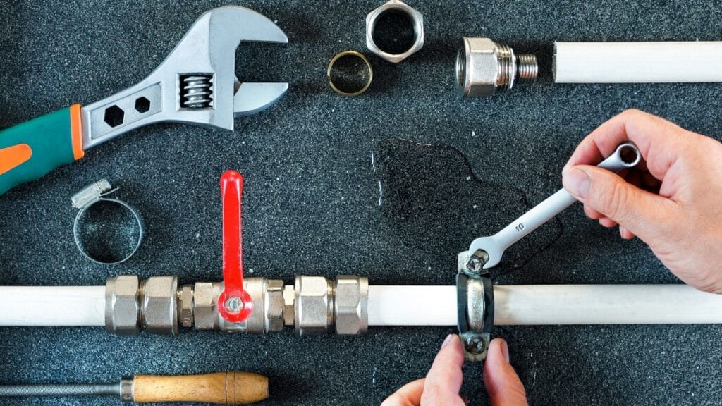 Plumber repairing a pipe valve with an adjustable wrench in Redlands