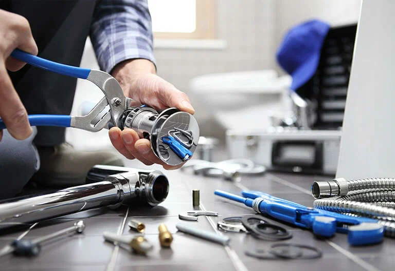 Technician repairing a plumbing fixture with professional tools in Redlands