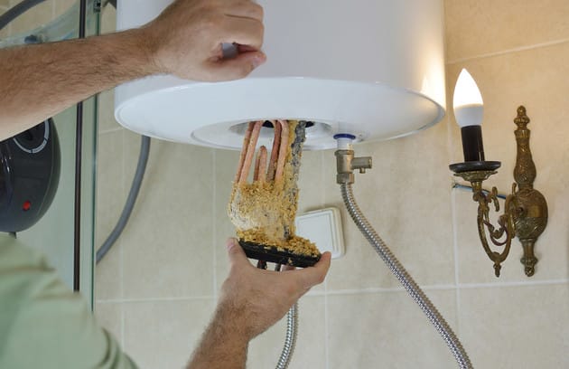 Technician removing mineral buildup from a water heater in Redlands