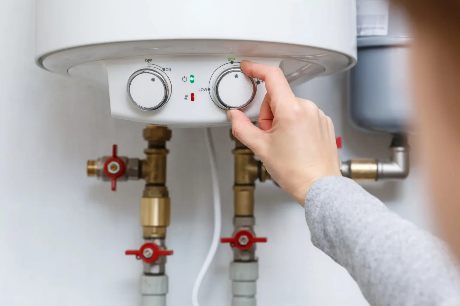 Homeowner adjusting the temperature controls on a water heater in Redlands
